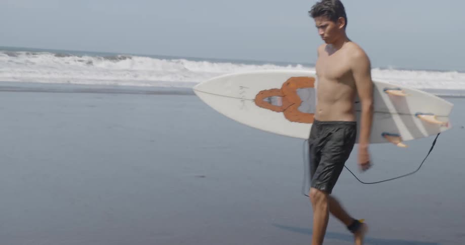 A man walks through the sand with his board