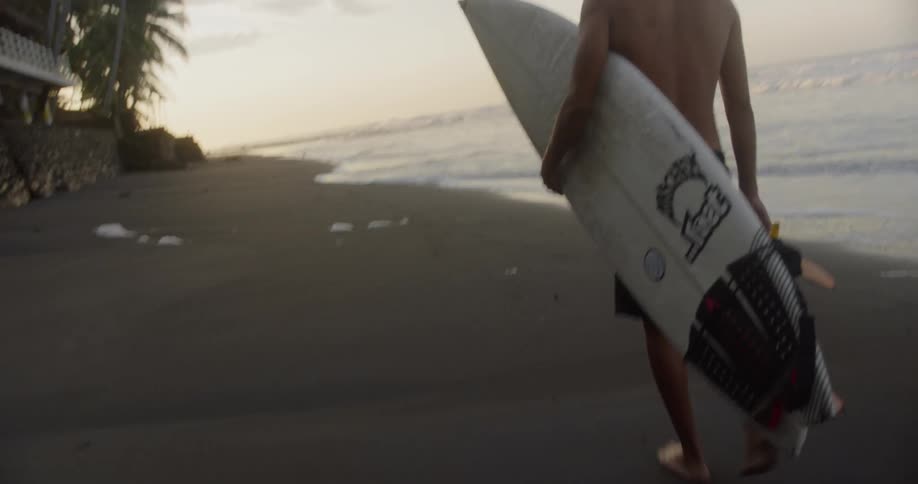 A man walks down the beach with his surfboard