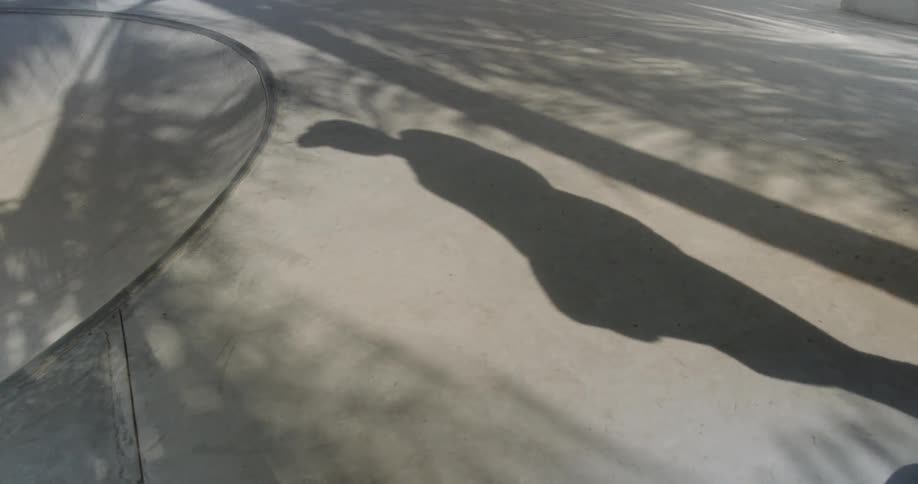 Shadow of man popping skateboard up and carrying it off