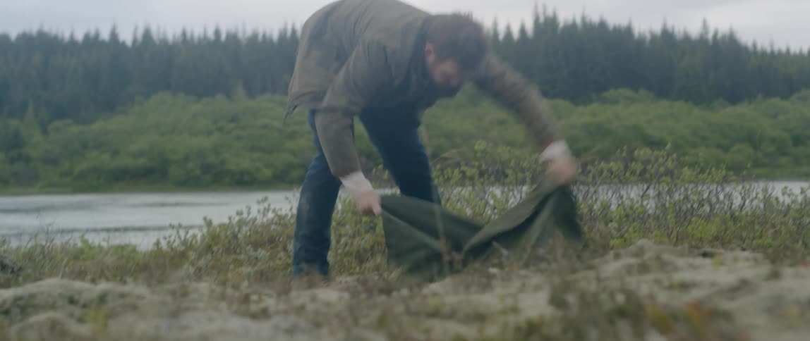 A man sets up his tent in a spot along the river