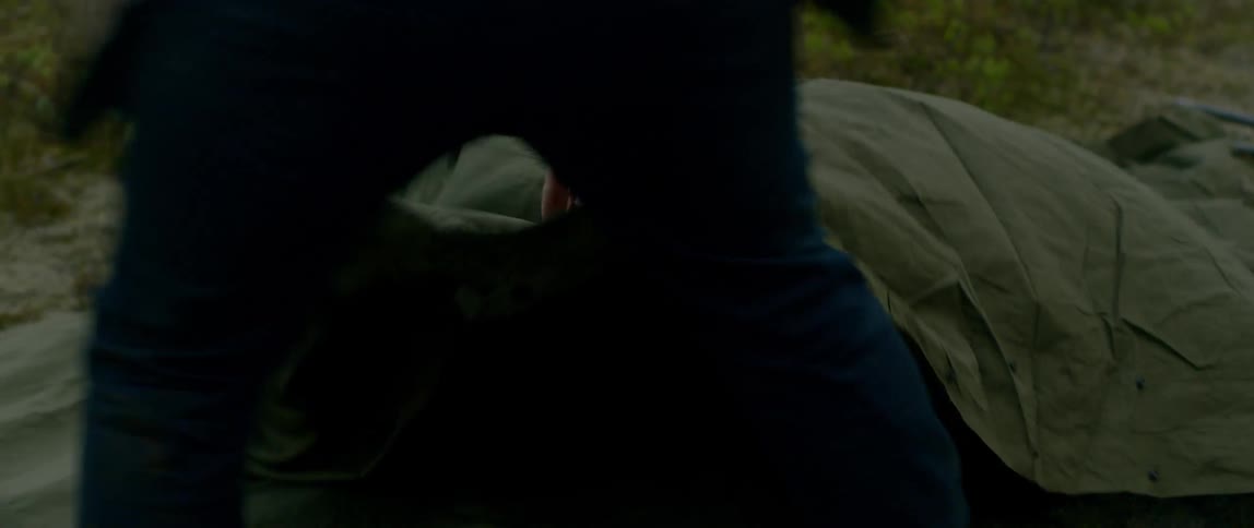 A white man unfolds a tarp outdoors