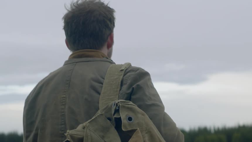 Man carrying backpack walking in a grassland alone