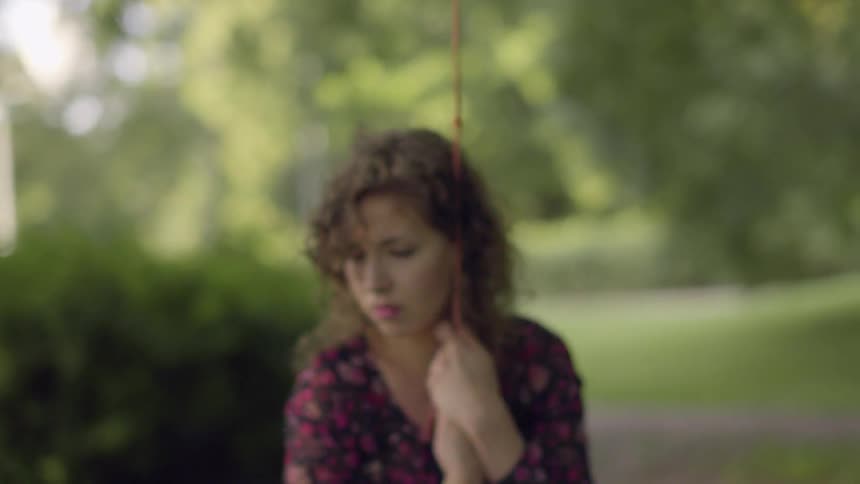 A woman looks sad while swinging outside
