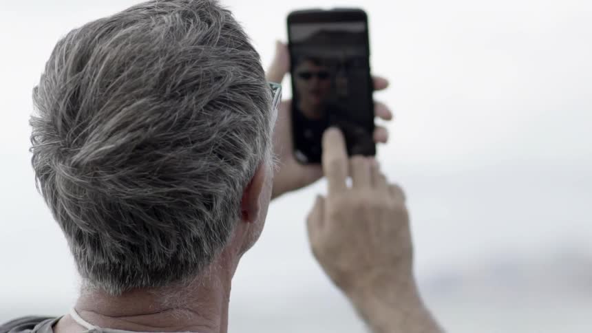 Person Using Phone Outdoors While Standing in Natural Light During Quiet Moment.