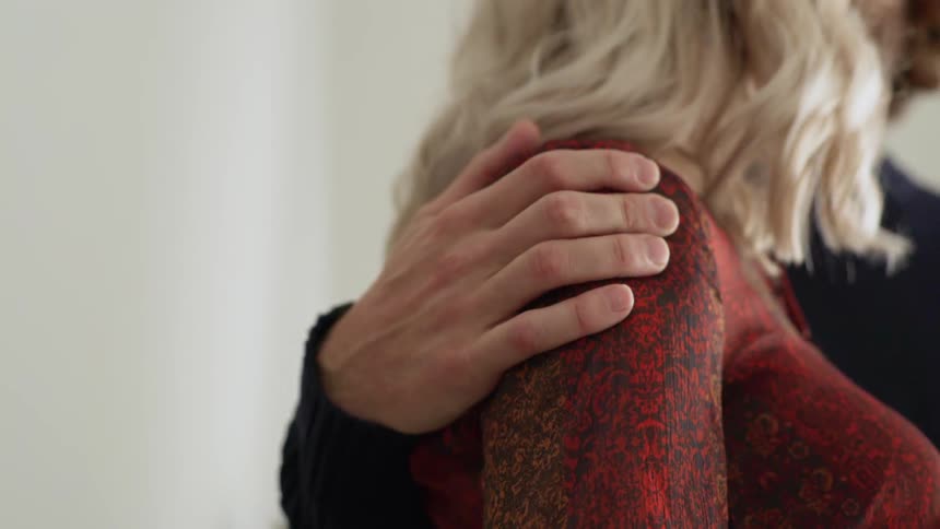 A man wraps his arms around a womans shoulder and squeezes