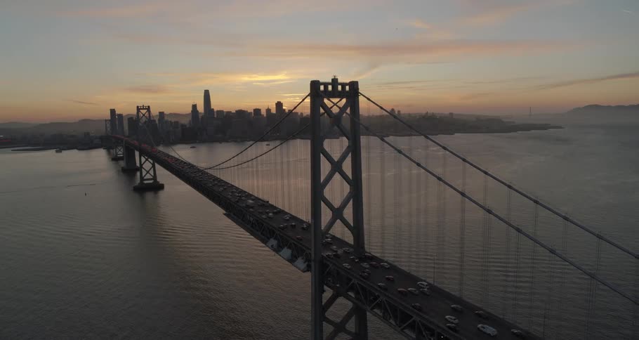 A scenery of a huge bridge crossing the river at sunset