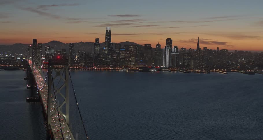Landscape view of a bridge over water leading in to a downtown area at night