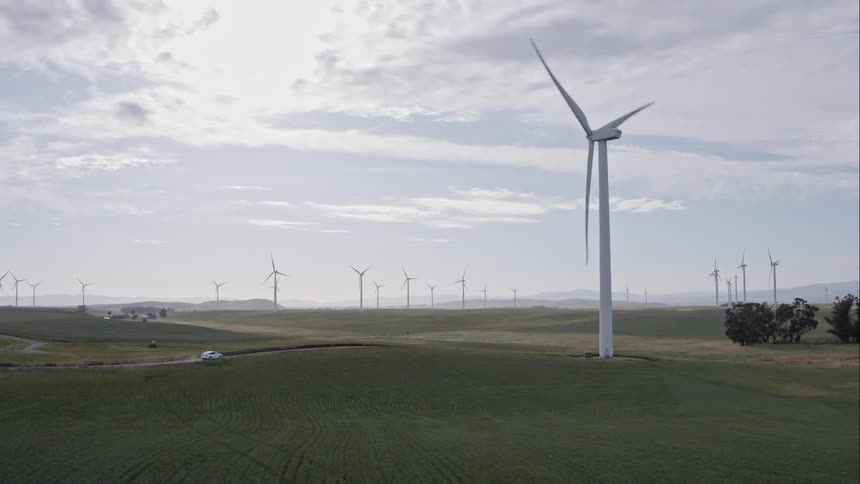Car drives on road through wind farm