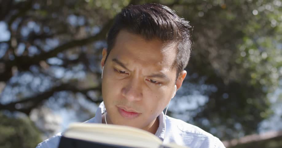 Man reads book while wearing a headset