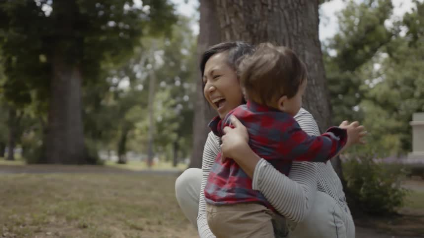 A child walks over and his mother picks him up