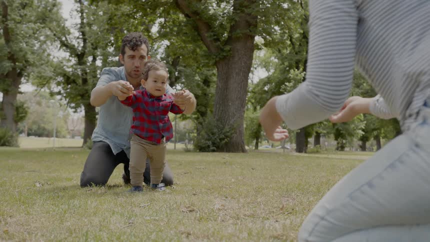 Couple teaching son to walk on a park