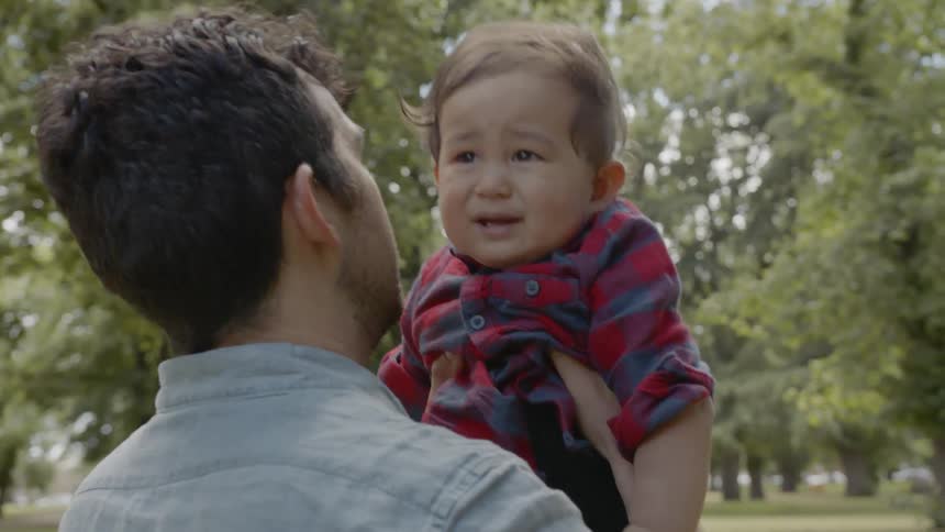 A man holds a crying baby outside
