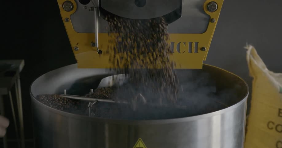 A person operates a machine to roast coffee beans