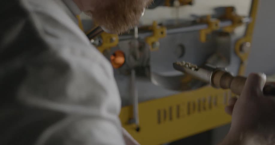 A man checks coffee beans from a roasting machine