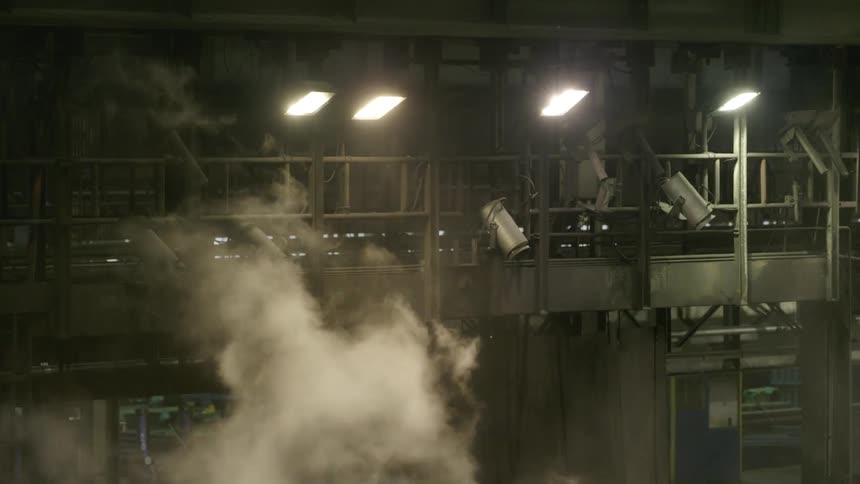 Smoke rises up towards the lights in a factory