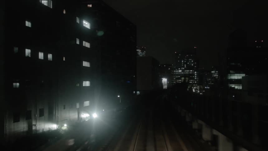 The train moves past the city at night