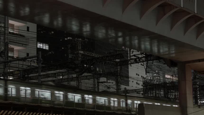 Two trains pass each other in the night in an urban area
