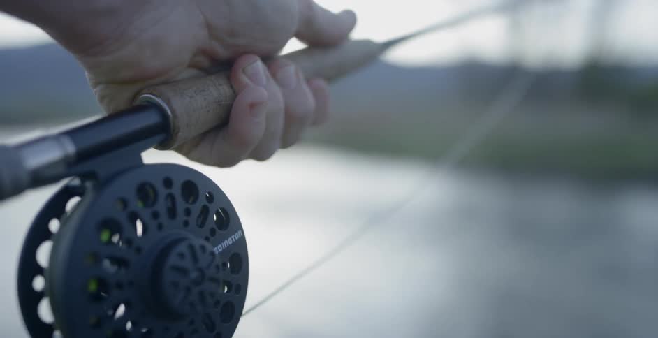 A white man casts a throw with a fly rod and reel