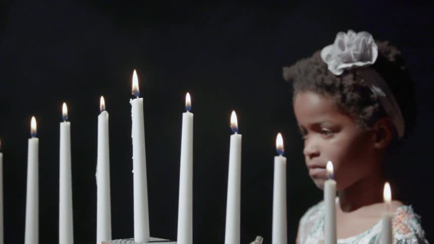 A girl is standing by a row of candles