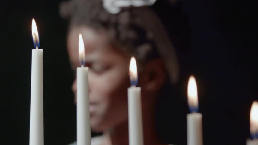 A young girls walks towards burning candles and looks at them