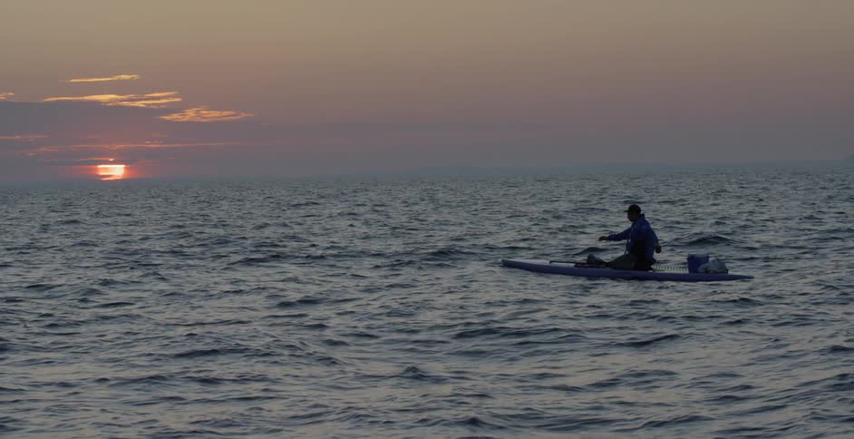 A person sitting in a kayak doing shoulder stretches