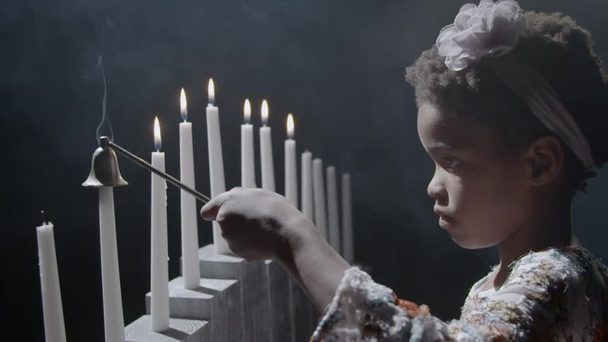 A child snuffs out a row of candles