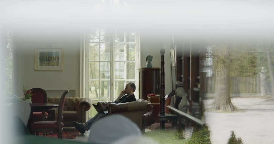 A man sits in a chair talking on the phone in a living room