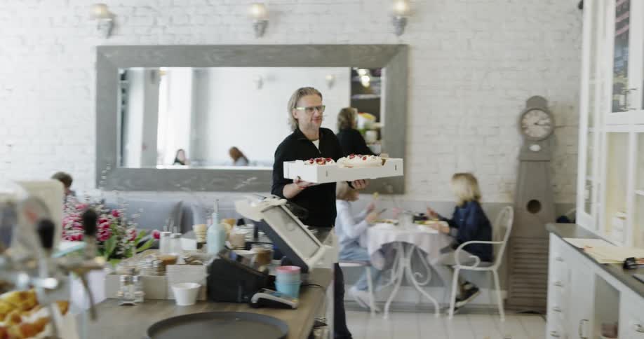 A person enters a business carrying cakes