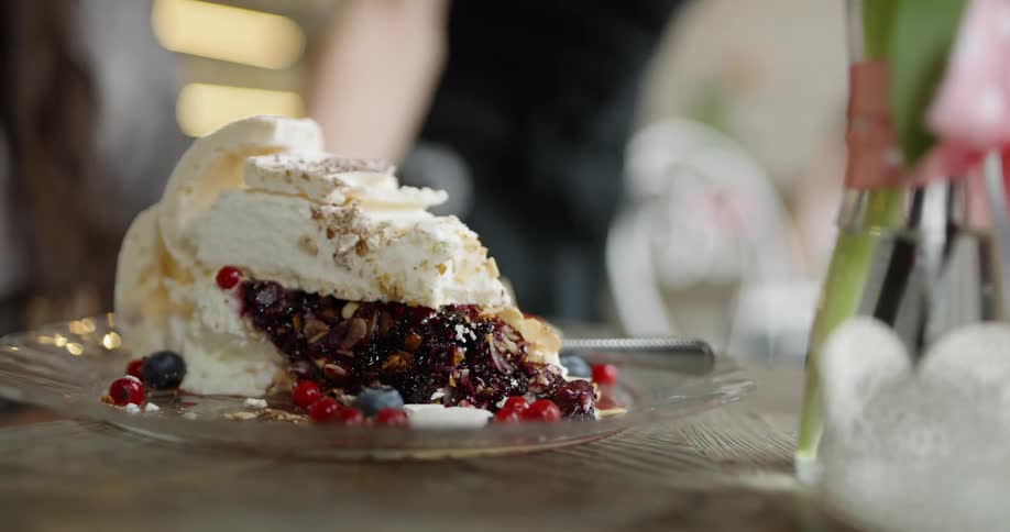 A server places a large piece of fruit pie down in front of a diner