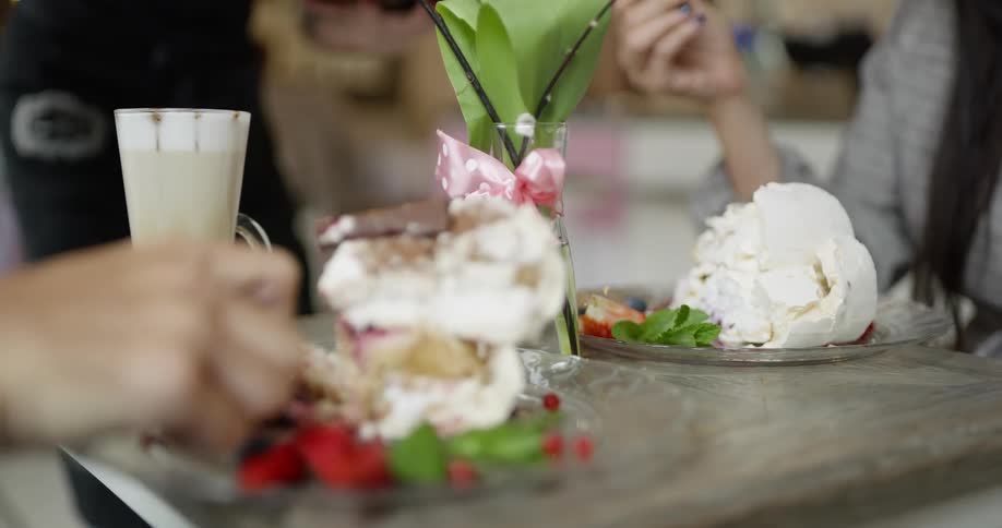 Two people eating dessert and a server brings more to the table