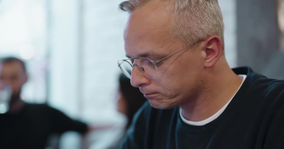 An older white man sits in a room