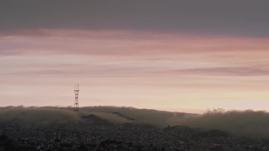 Clouds float above city buildings at sunset