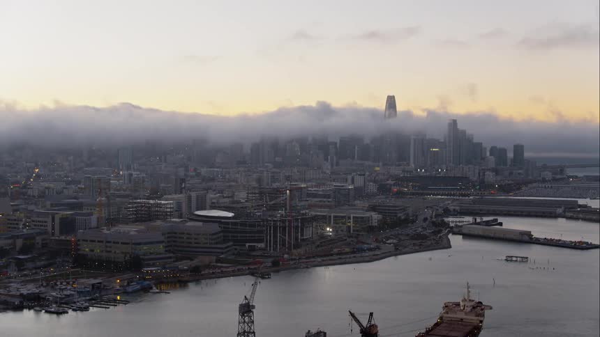 Low clouds roll across the top of a large coastal city