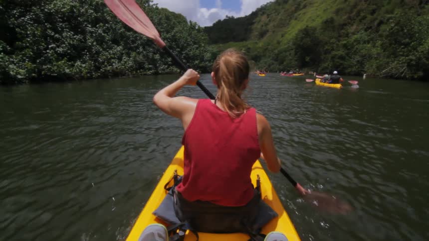 Woman in a red tank paddles the kayak down the river