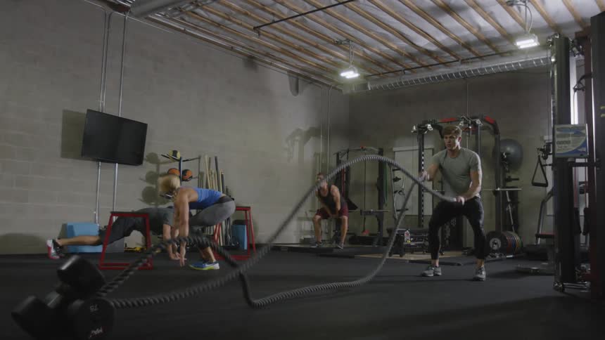 Three men and a woman work out in a gym during daylight