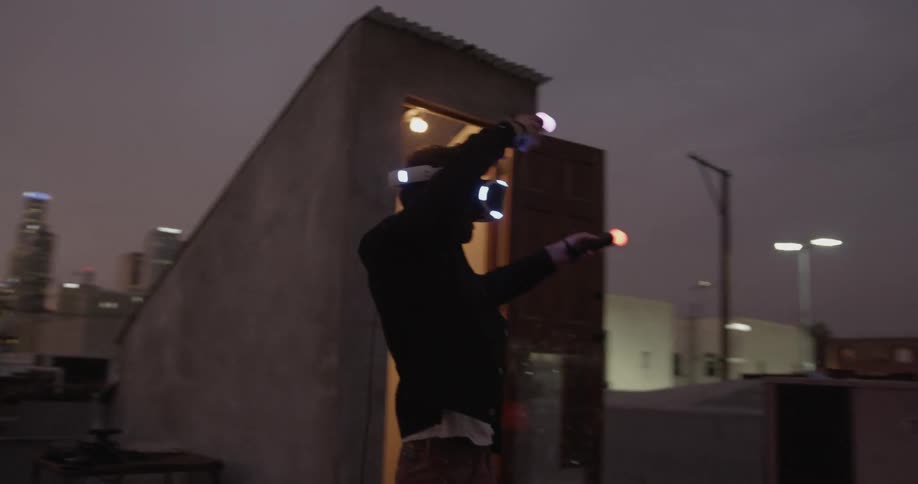 A man using a virtual reality headset on a rooftop at sunset
