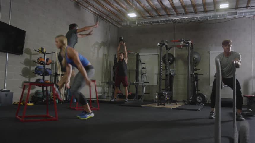 A muscular woman and three men work out in the gym