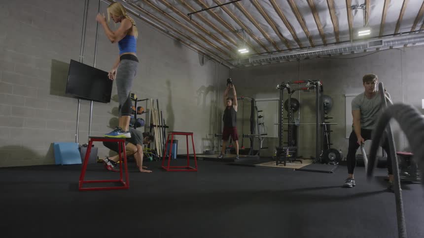 Three men and a woman work out in a gym during daylight