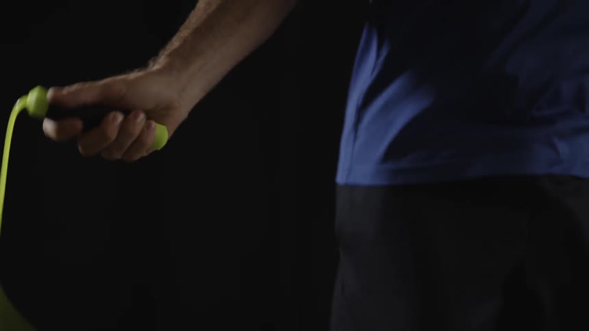 Man jumps yellow rope on the black background