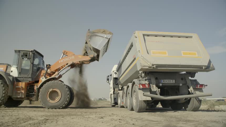 A front end loader dumps dirt into a truck
