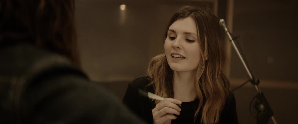 A young woman faces another person and talks with them
