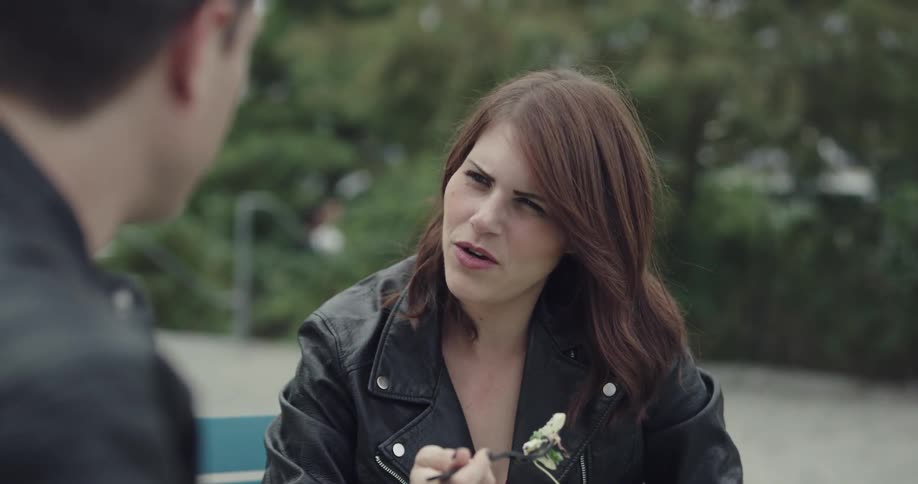 A woman with food on her fork listens to a man speaking across from her