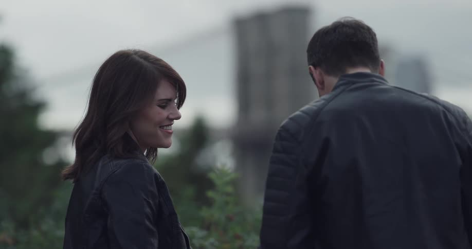 A man and woman stand together talking and laughing
