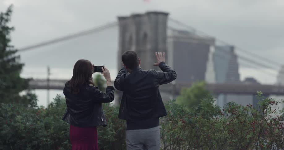A man and woman look at a building and take pictures