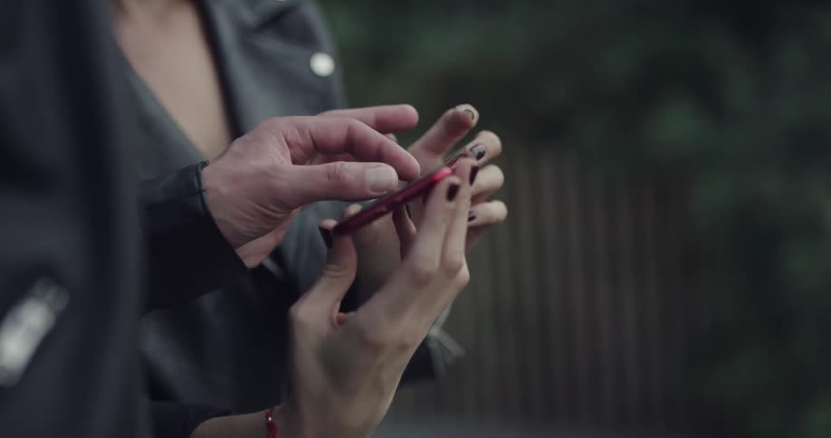 A man and woman smile and take a photo with a smartphone outside