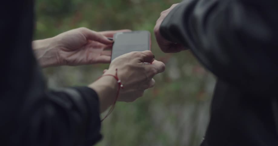 A woman laughs and shows a man something on her cell phone