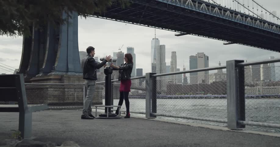 Couple having fun while looking through a viewfinder in the city