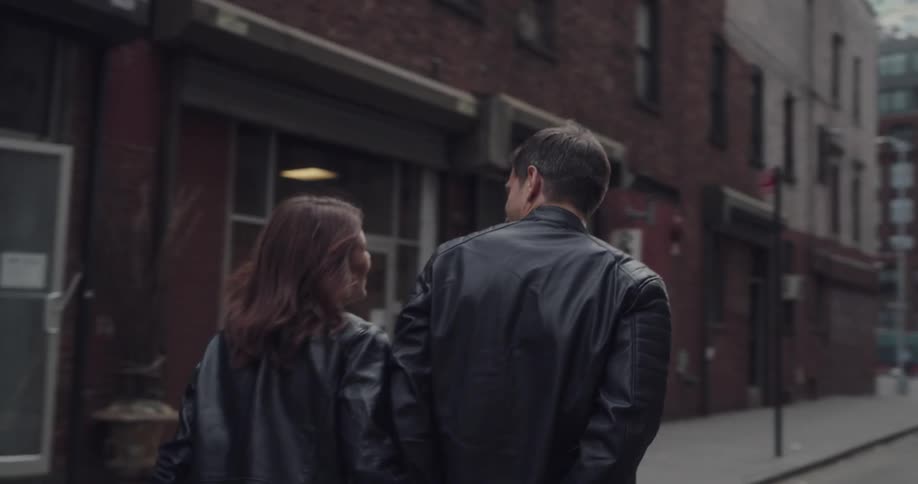 A male and female are holding hands and walking in a town