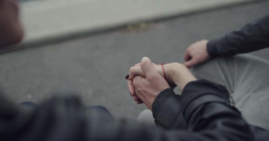 Couple holding hands outdoors while sitting on a bench