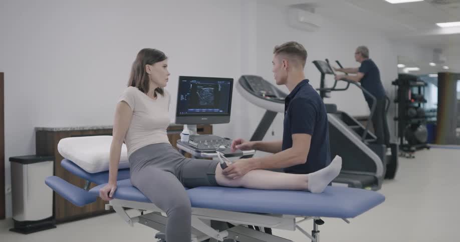 Technician performs ultrasound examination on womans knee